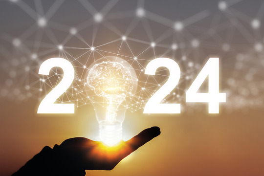 Image of hand holding the number 2024. The digit 0 in 2024 is represented by a lightbulb.