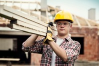 young construction worker lifting materials on site