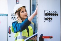 females worker in PPE, on site, checking electrics