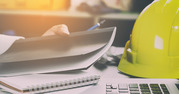 hard hat and papers strewn across a busy desk