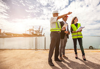 workers in discussion, wearing PPE, at port