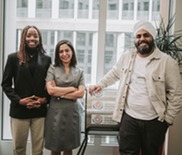 Three people standing in office, next to a manual washing machine