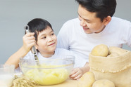 Dad cooking mash potatoes with child