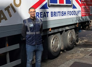 Joseph standing in front of a lorry bearing the words "Great British Foodlift"