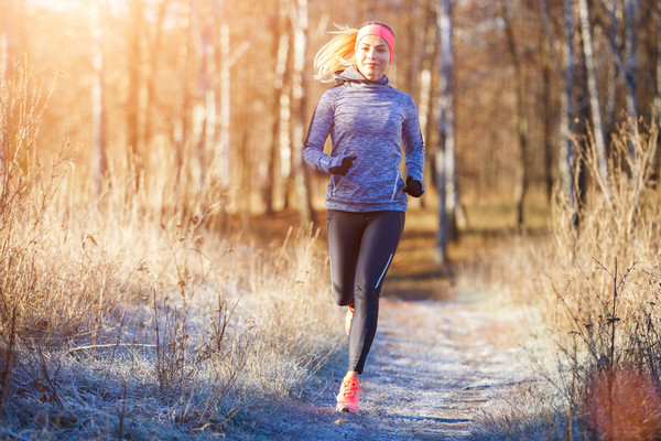 Woman running through a forest on a cold autumn or winter morning