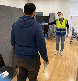 Vaccine volunteer welcoming a resident at a vaccination centre