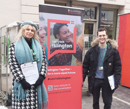 Smiling woman and man in front of a pop up banner for Let's Talk Islington