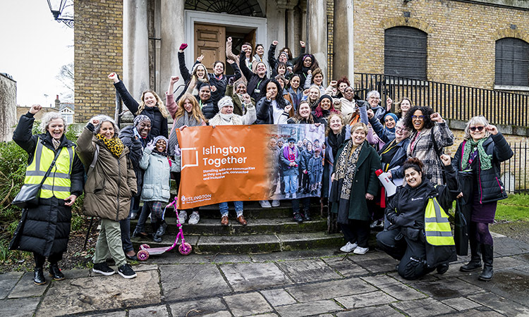 A group of Islington women cheering infront of a building holding a sign that says 'Islington Together'