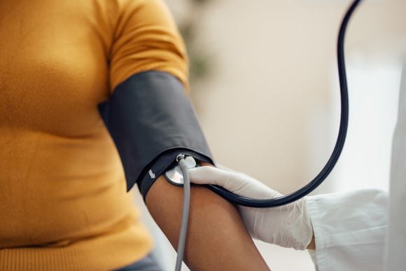 A person having their heart rate and blood pressure measured by a doctor