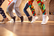 People's legs in different types of trousers all dancing and jumping in a gym dance studio