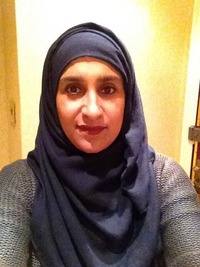 A woman wearing a black hijab, smiling at the camera