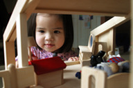 Asian child playing with a dolls house