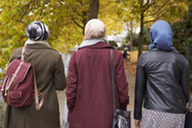 Three woman walking together. The image is taken from behind. They are all wearing hijabs.