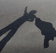 A shadow of a child in a superhero pose with their arm outstretched and a cape