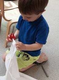 A child using scissors to cut a white pillow case