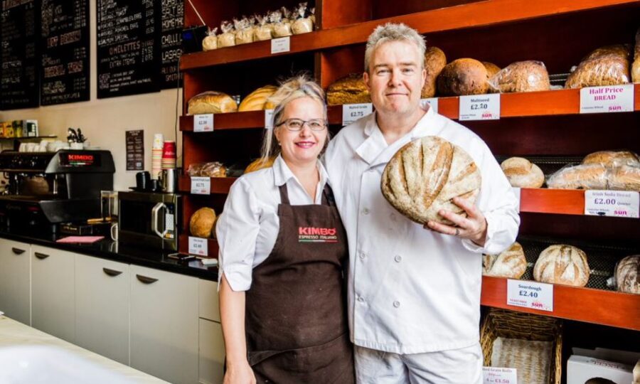Two Islington bakers in an artisanal bakery holding bread and smiling