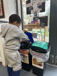 A young boy putting an item in a recycling box