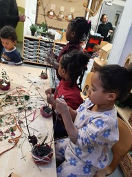 A small group of young children, sitting at a table using natural resources for a creative activity
