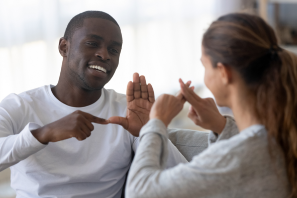 Two people smiling and using sign language