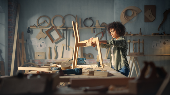 Person building a chair out of wood in a woodworking shop