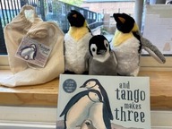 Some small toy penguins with the book 'And Tango makes three'