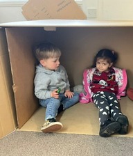 Two young children sitting inside a cardboard box