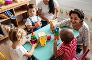 A group of children playing with a childcare worker in a nursery setting