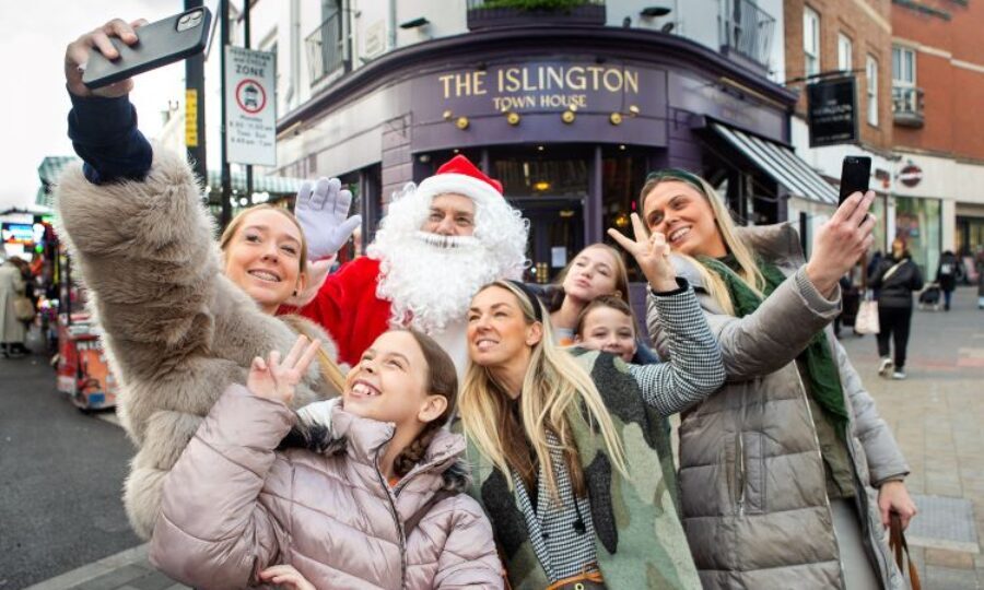 A group of girls and boys smiling posting with Santa in Islington