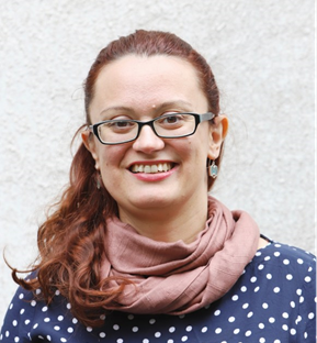 Photo of a young woman wearing glasses. She is smiling