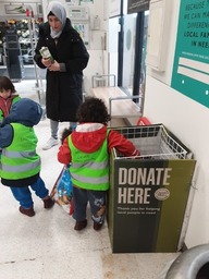 A young child putting a food item into a food bank basket in a supermarket