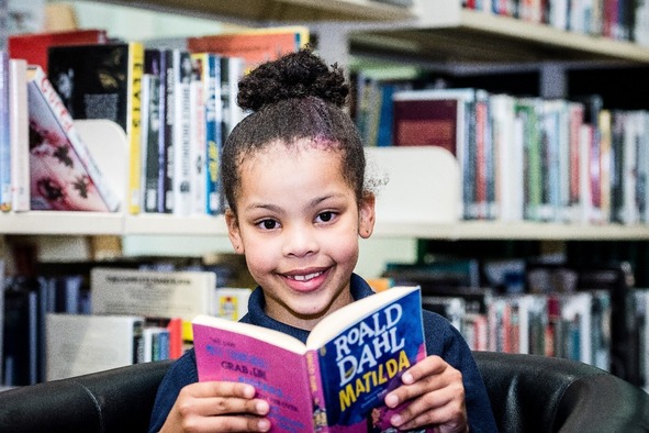 little girl holding roald dahl book and smiling