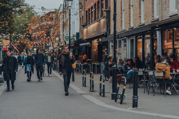 local highstreet with people walking, sitting out side restaurants and christmas light