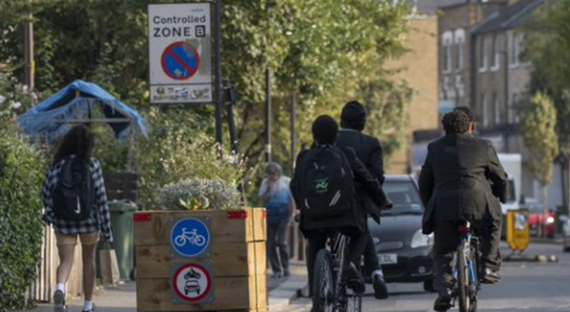 Young people ride bikes through a traffic filter planter