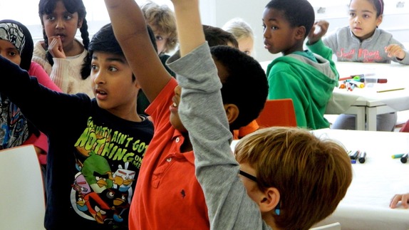 a group of children with one putting his hand up 