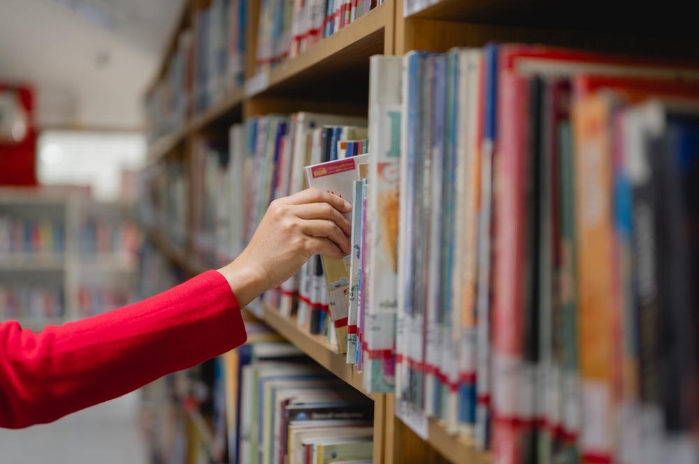 hand selecting a book from library shelf