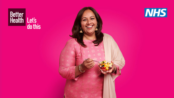 NHS photo with a woman smiling in front of a pink background