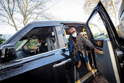 Passenger stepping out of black taxi