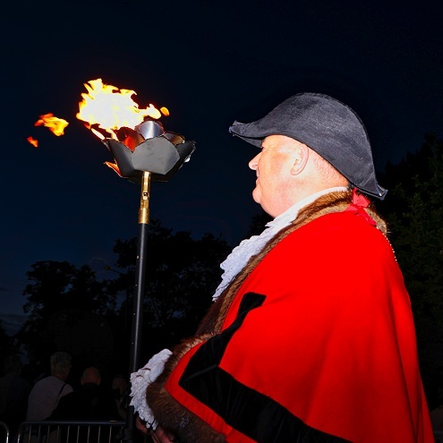 Mayor standing beside lit beacon