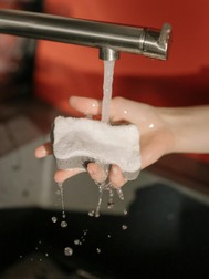 Someone running a sponge under a tap