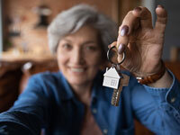 Image of woman holding up a bunch of keys with a house-shaped keyring