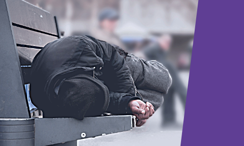 A person lying down on a public bench