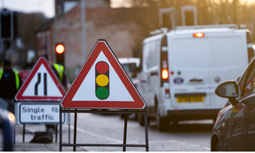 Street with cars and roadworks signage 