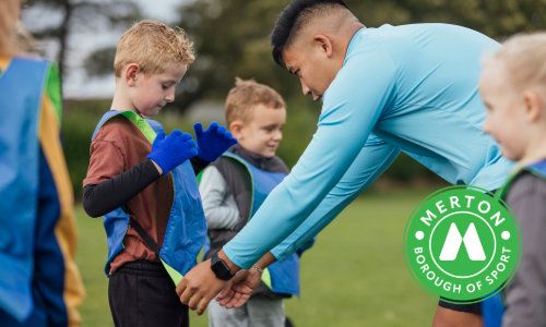 Coach helping a child put on a sports bib