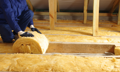 Worker installing insulation in an attic.