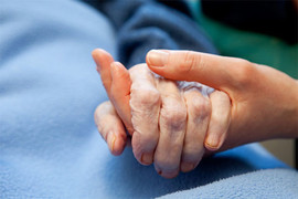 The hand of an elderly lady being held by her carer's