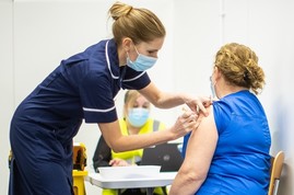 Vaccine being given by nurse in royal blue scrubs