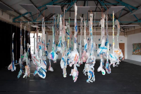 recycled plastic sculpture hanging in a warehouse