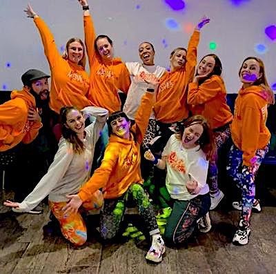 Group of dancers in matching orange jumpers