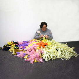 woman sitting on the floor weaving