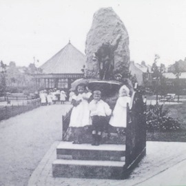 Black and white image of three children standing on sculpture